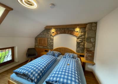Rustikales Schlafzimmer mit Steinmauer im gemütlichen Dachgeschoss